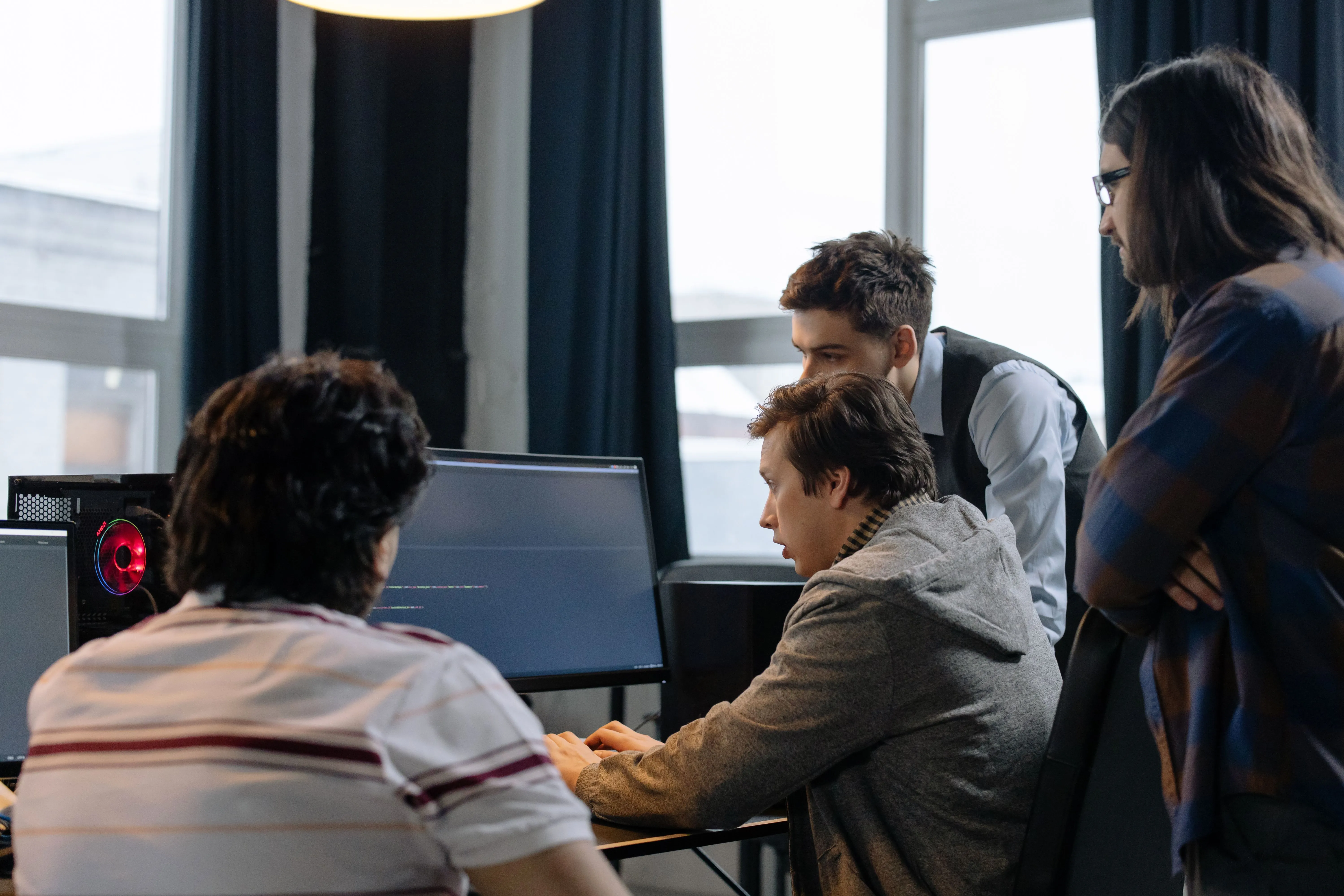 Equipe reunida analisando código em computadores no escritório