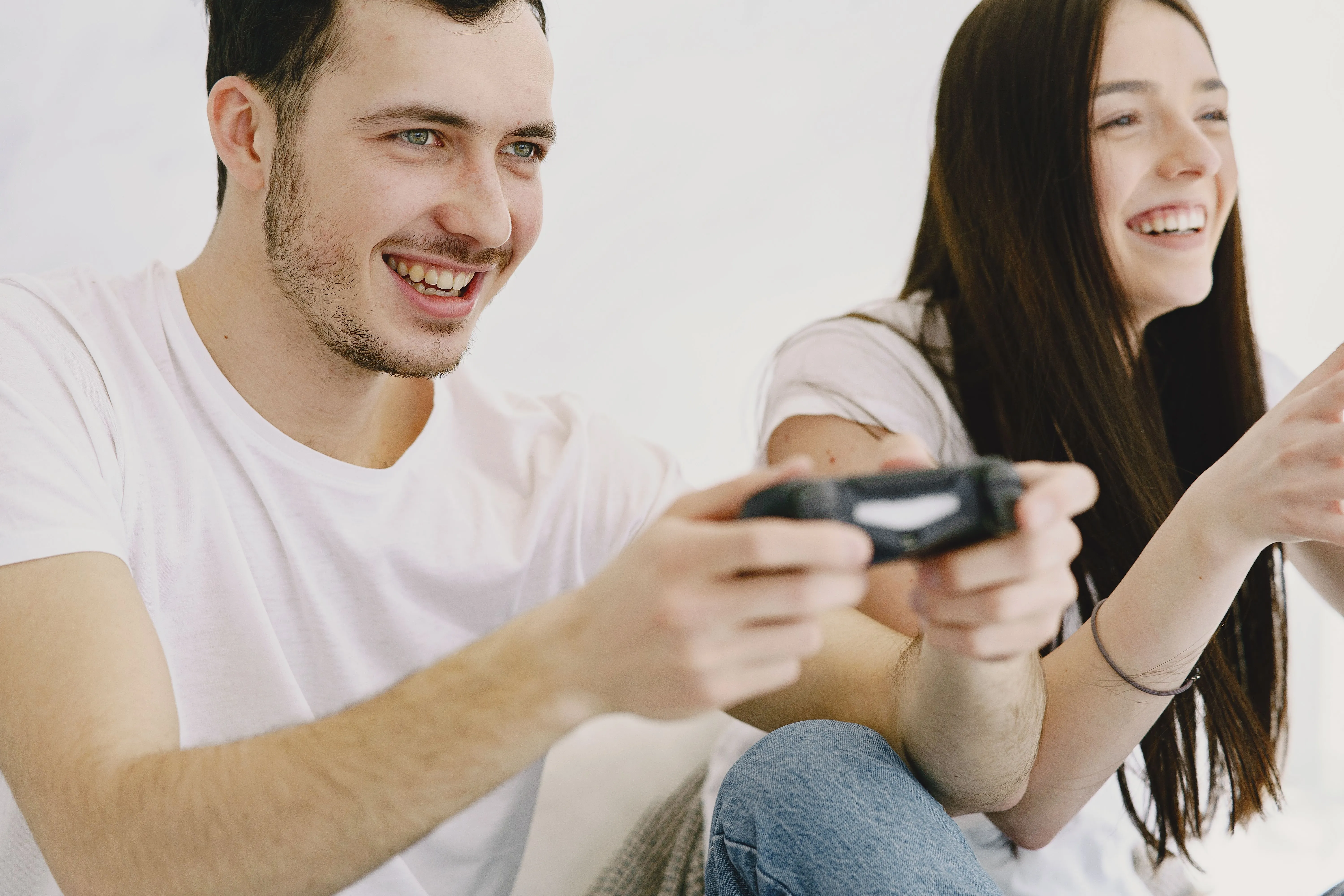 Casal sorrindo enquanto joga videogame com controles na mão