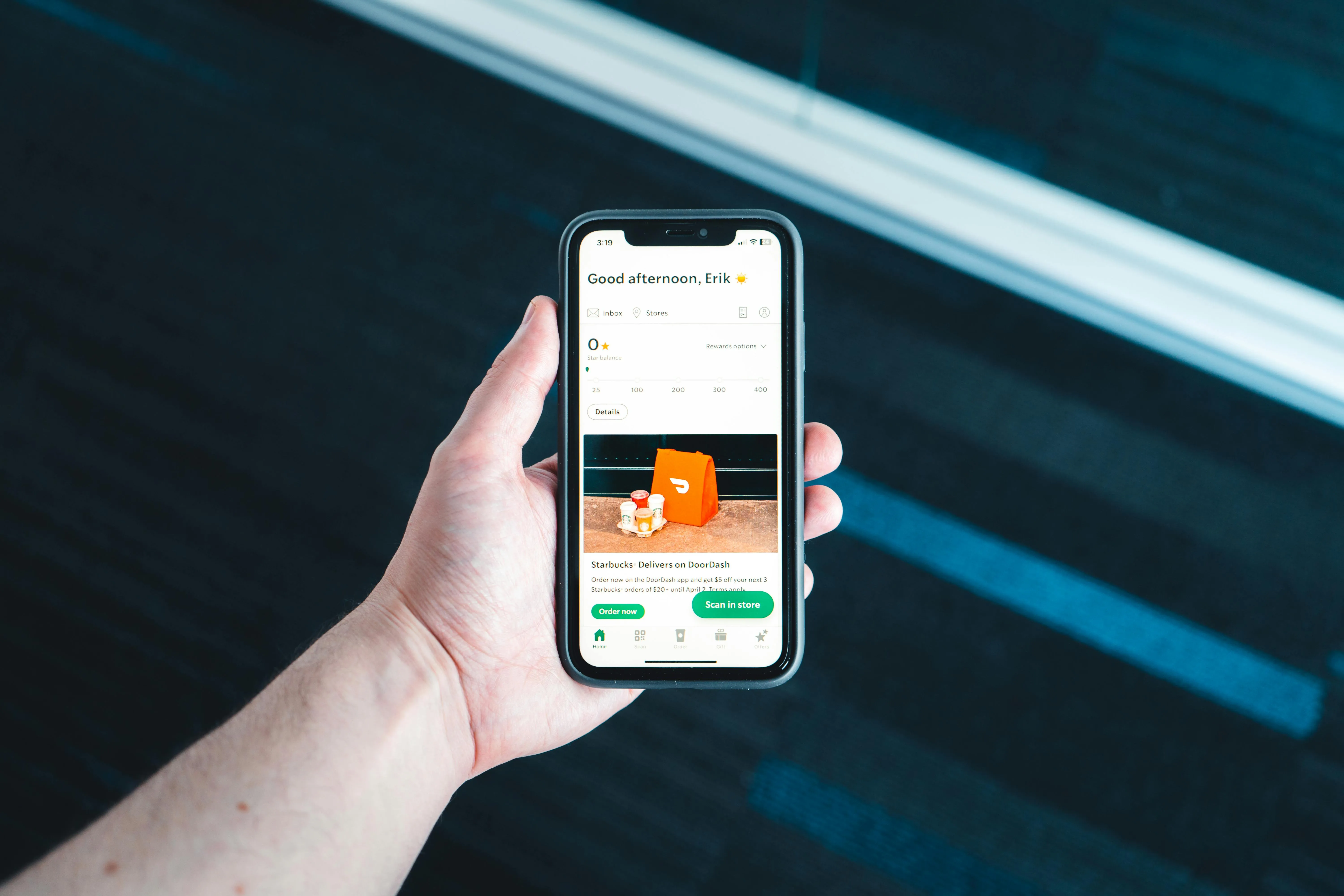 Pessoa segurando celular com aplicativo de recompensas aberto.