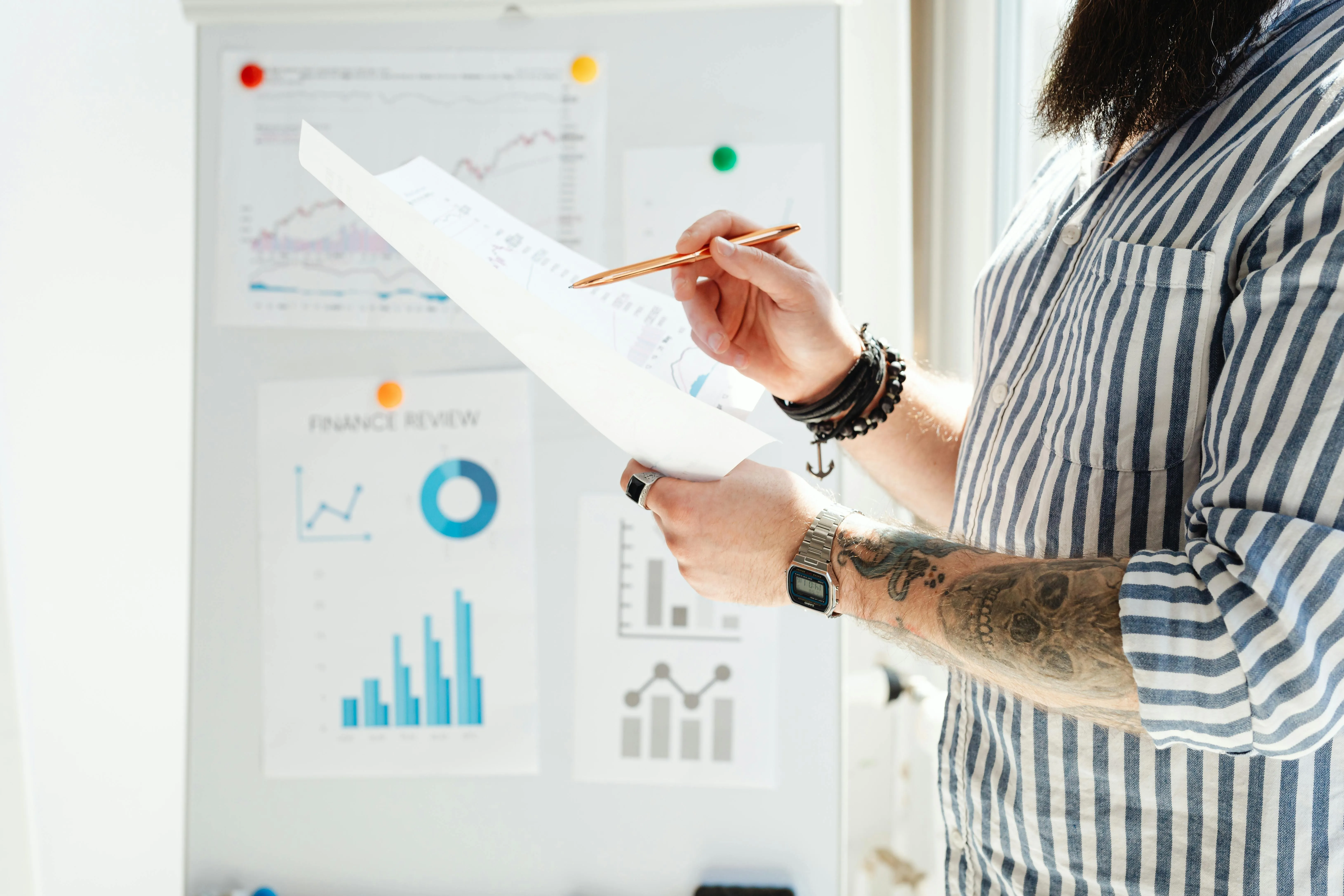 Pessoa analisando gráficos e relatórios financeiros em papel.