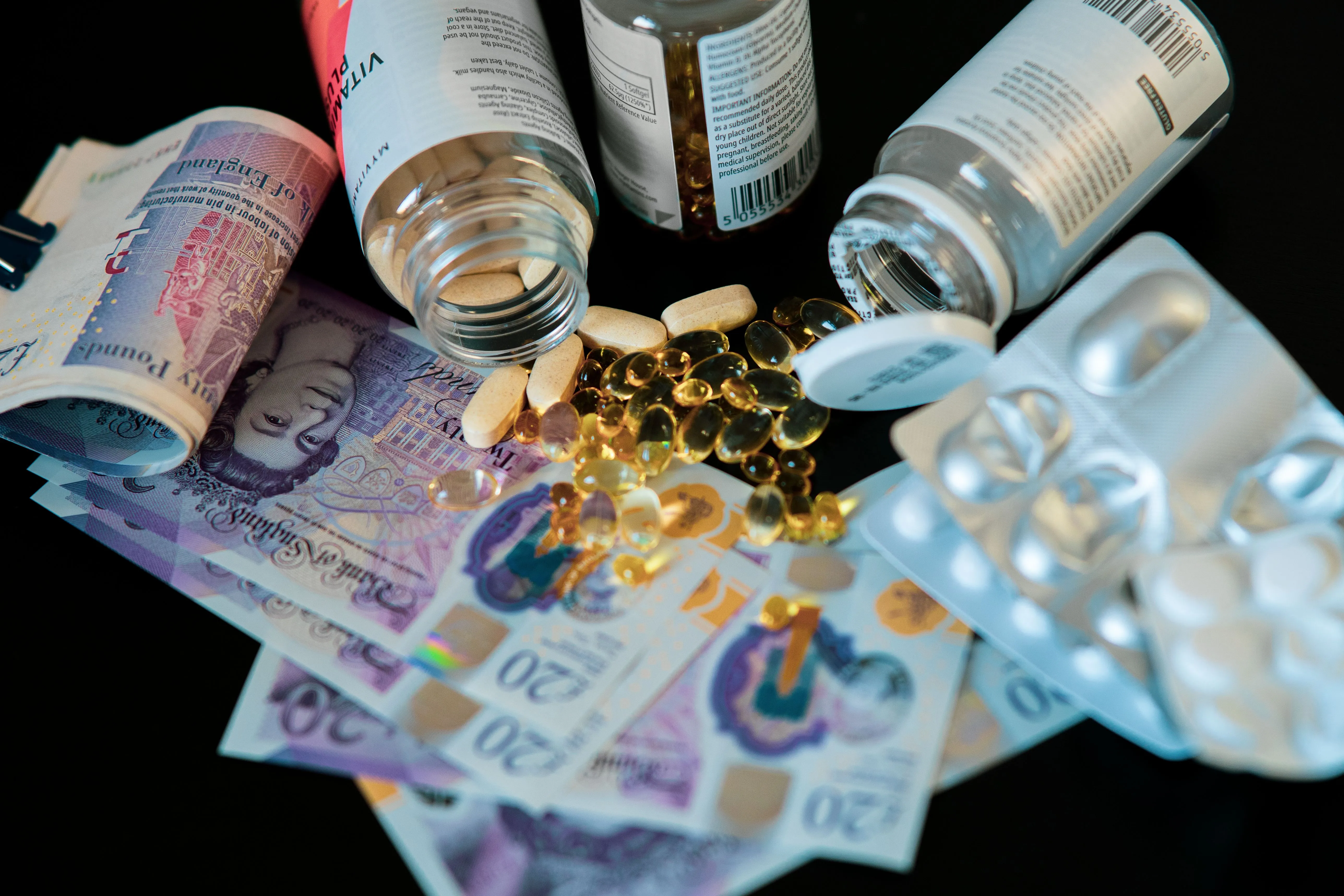 Frascos de medicamentos e comprimidos sobre cédulas de dinheiro.