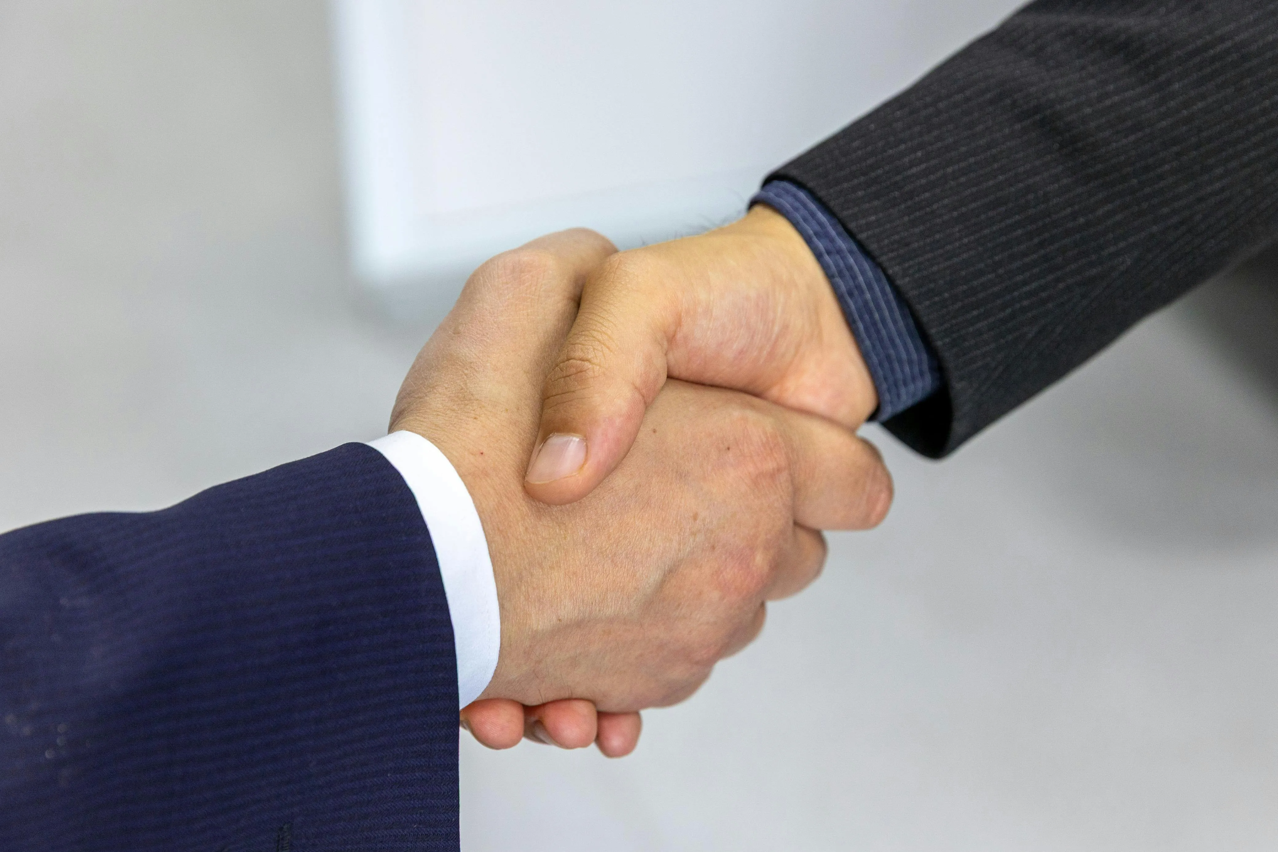 Aperto de mãos entre pessoas de terno em ambiente corporativo