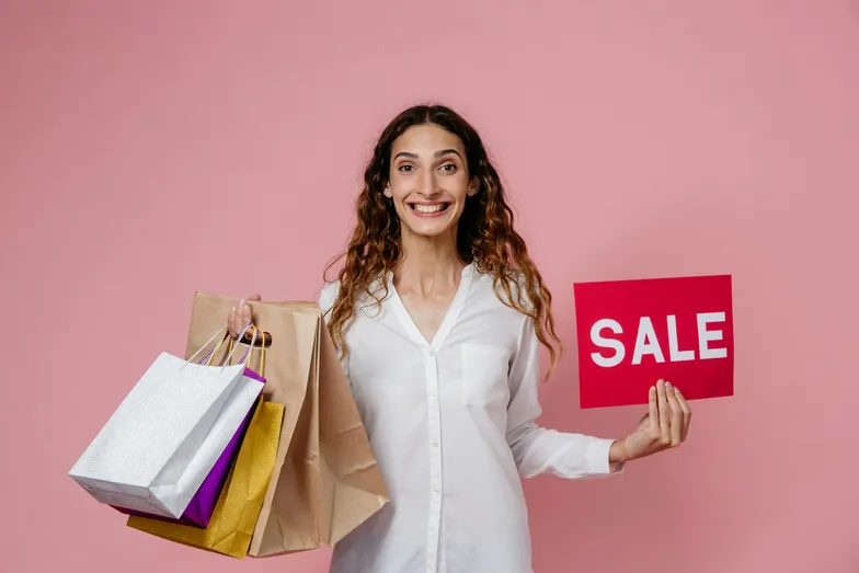 Mulher com sacolas de compras segura placa de promoção SALE