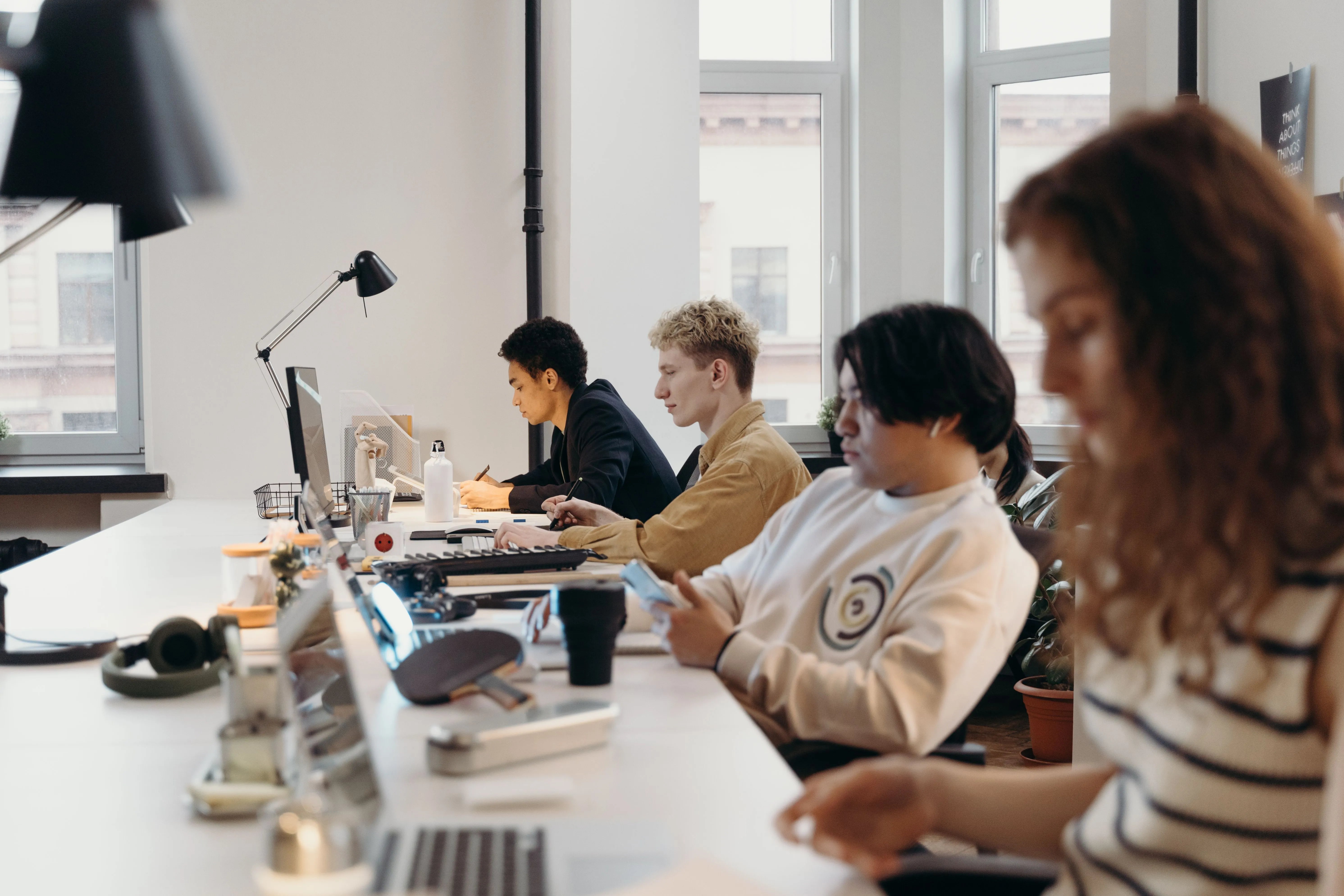 Equipe trabalhando em escritório compartilhado com computadores e celulares.