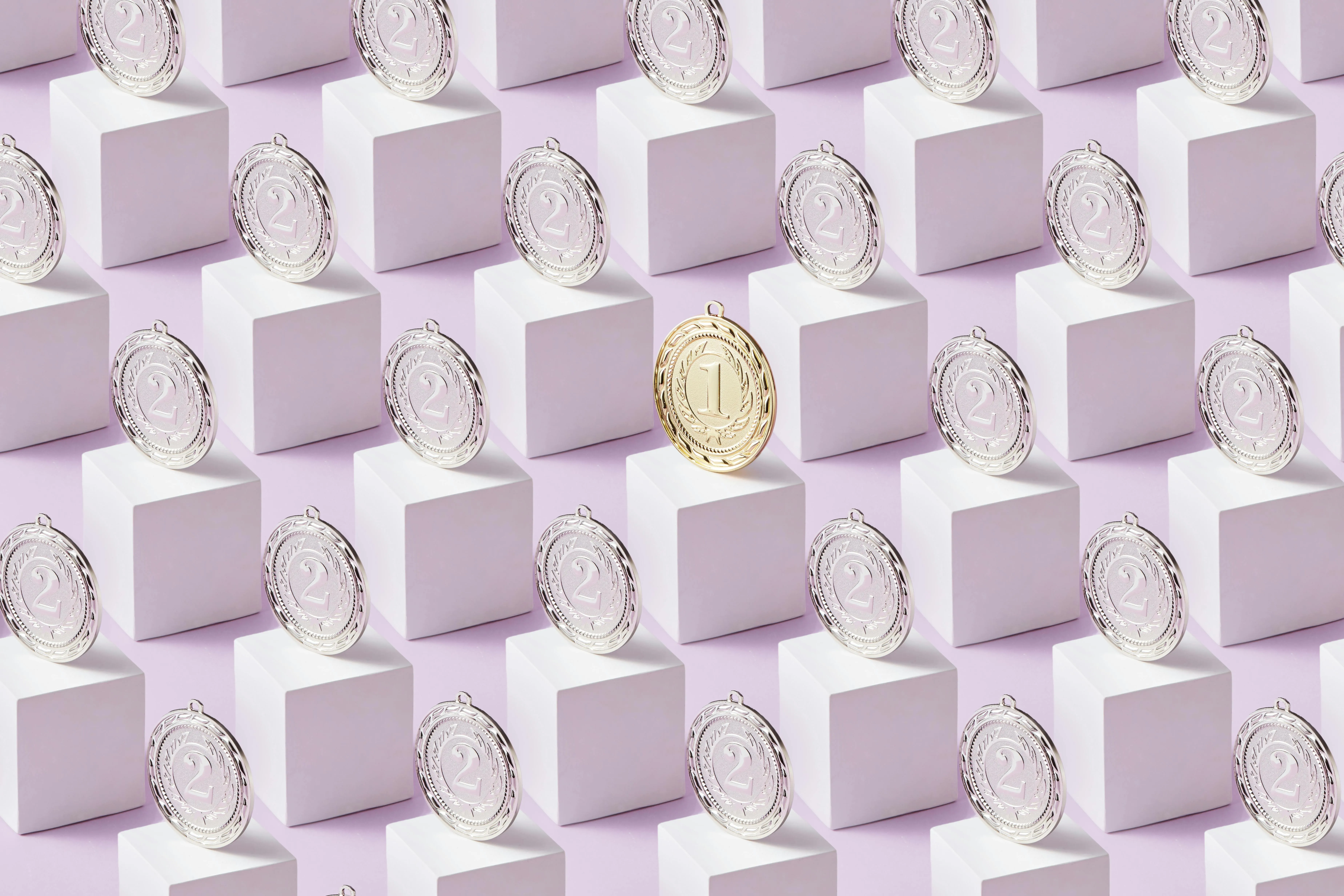 Medalhas prateadas e uma dourada destacada sobre blocos geométricos