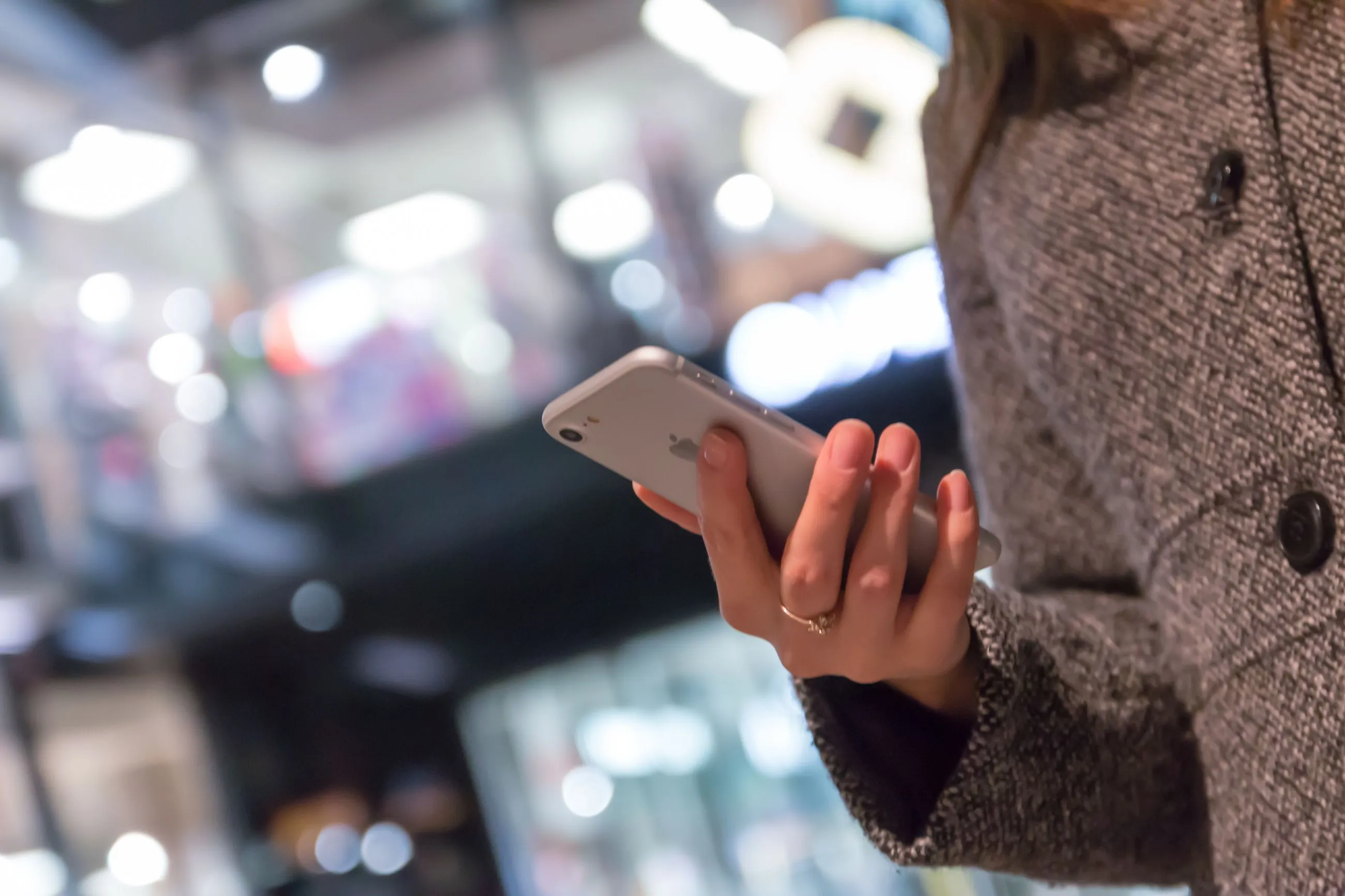 Pessoa usa celular em um ambiente comercial.