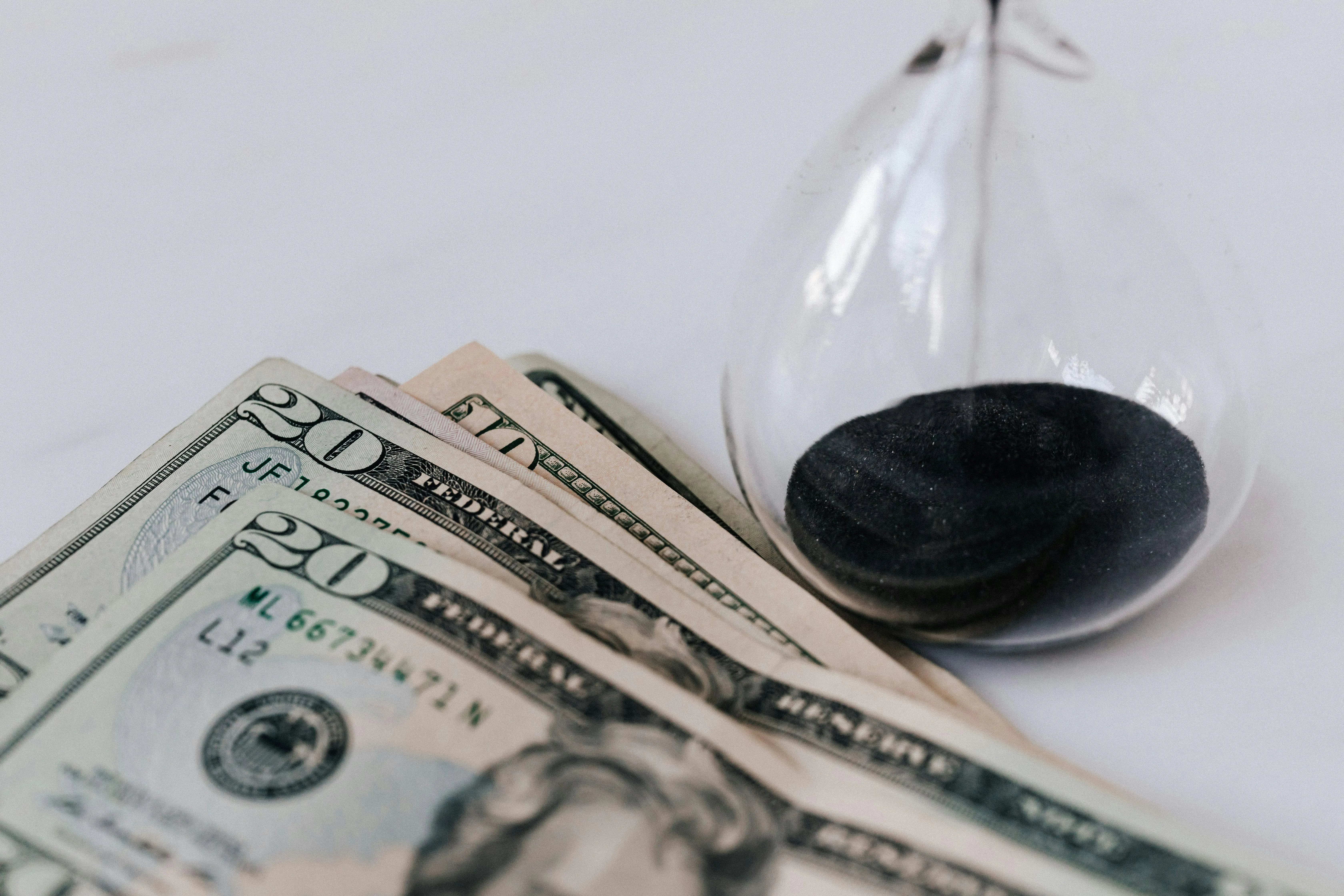 Notas de dólar ao lado de ampulheta simbolizando tempo e dinheiro